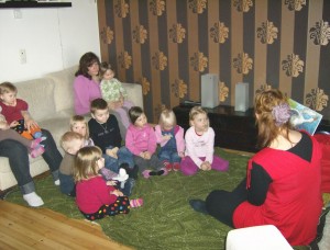 Satutuokio perhepäivähoitajan kotona. Lapset istuvat lattialla ja kuuntelevat satuja.