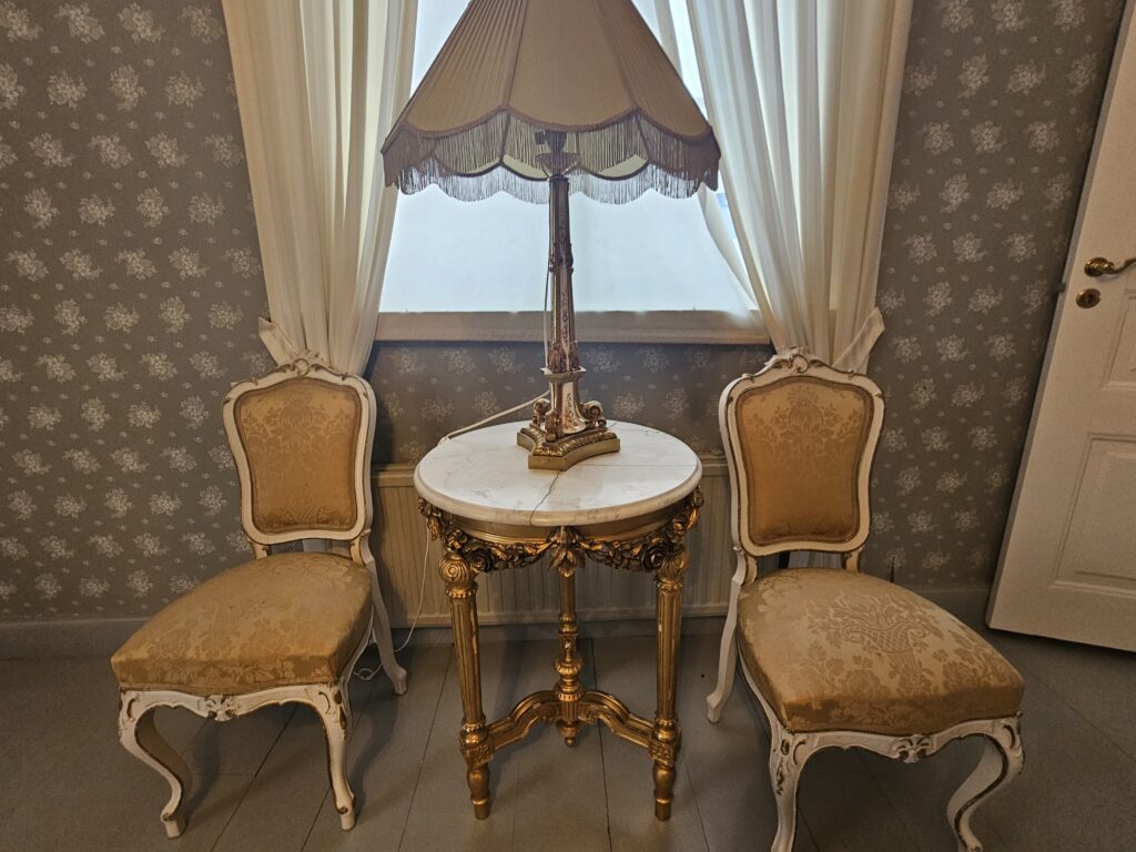 Törnävän kartanolta kuva, jossa on lamppu, pöytä ja kaksi tuolia