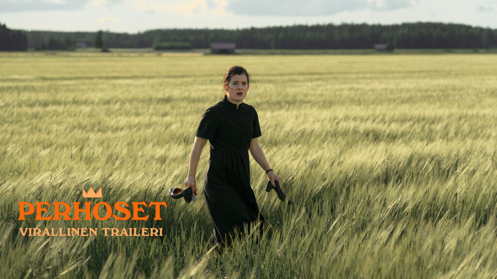 Perhoset-elokuvan pääosanäyttelijä Aksa Korttila viljapellolla korkokengät kädessä. Hänen kasvoillaan on hämmentynyt ilme.